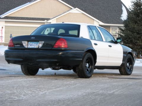 2000 Ford Crown Victoria - This 2000 Ford Crown Victoria features a distinctive black and white two-tone paint scheme and is seen from the rear three-quarter angle.