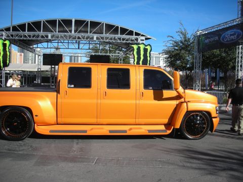 1998 Ford Crown Victoria - orange custom crew-cab medium-duty truck with lowered stance and DUB graphics shown in profile at an outdoor event.