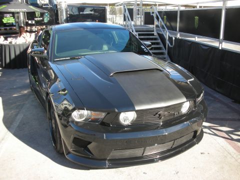 1998 Ford Crown Victoria - black Ford Mustang coupe with a vented hood, aggressive body kit and blacked-out grille parked at an outdoor event.