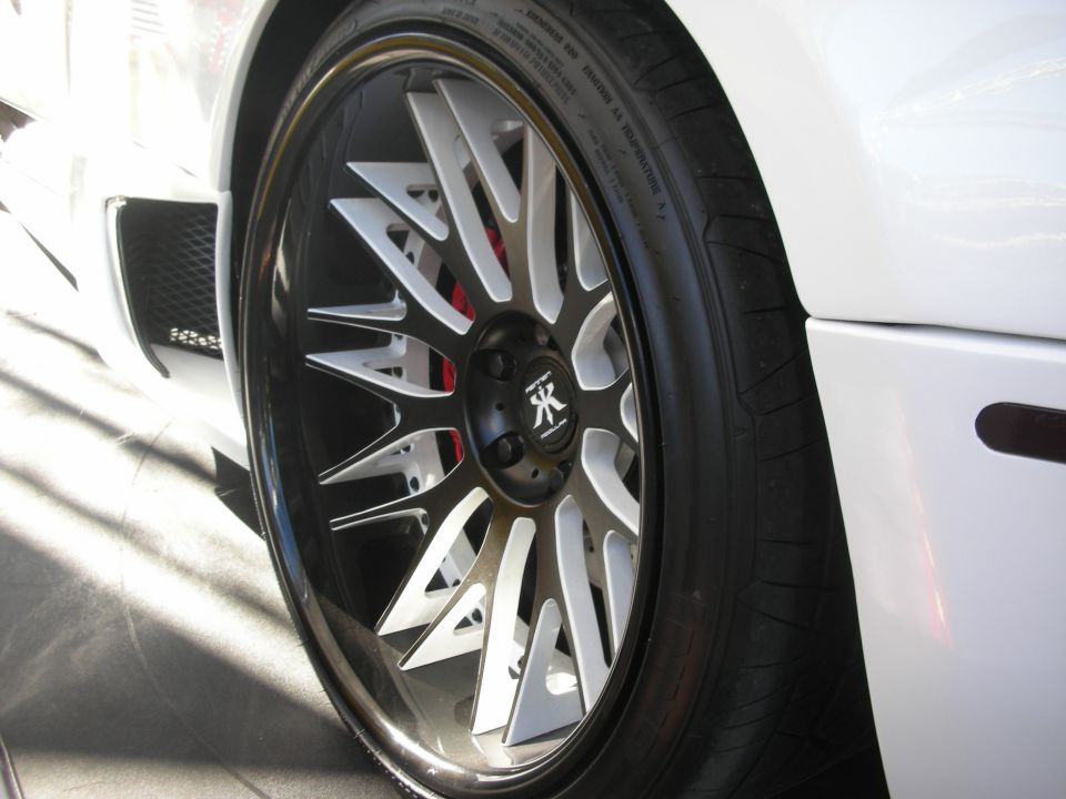 Black-and-silver multi-spoke wheel with red brake caliper on white car