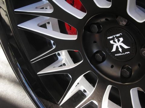 1998 Ford Crown Victoria - Close-up of a Rennen Modular wheel center cap surrounded by black-and-silver machined spokes and lug bolts.