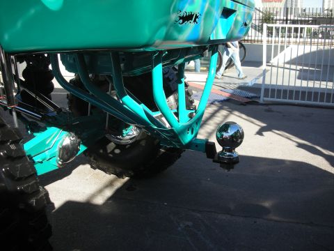 1998 Ford Crown Victoria - teal-painted rear chassis and suspension of a lifted vehicle, showing a ball hitch and oversized off-road tires.