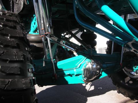 1998 Ford Crown Victoria - Underside view of a lifted truck showing a teal-painted solid axle, airbag suspension and large off-road tires.