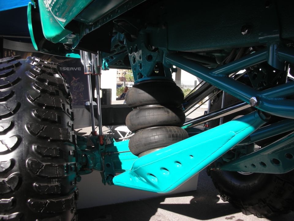Teal airbag suspension and control arms under a lifted off-road truck