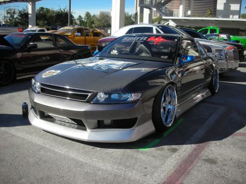 1998 Ford Crown Victoria - gray custom coupe with a wide body kit, slammed stance and chrome wheels parked at an outdoor car show.