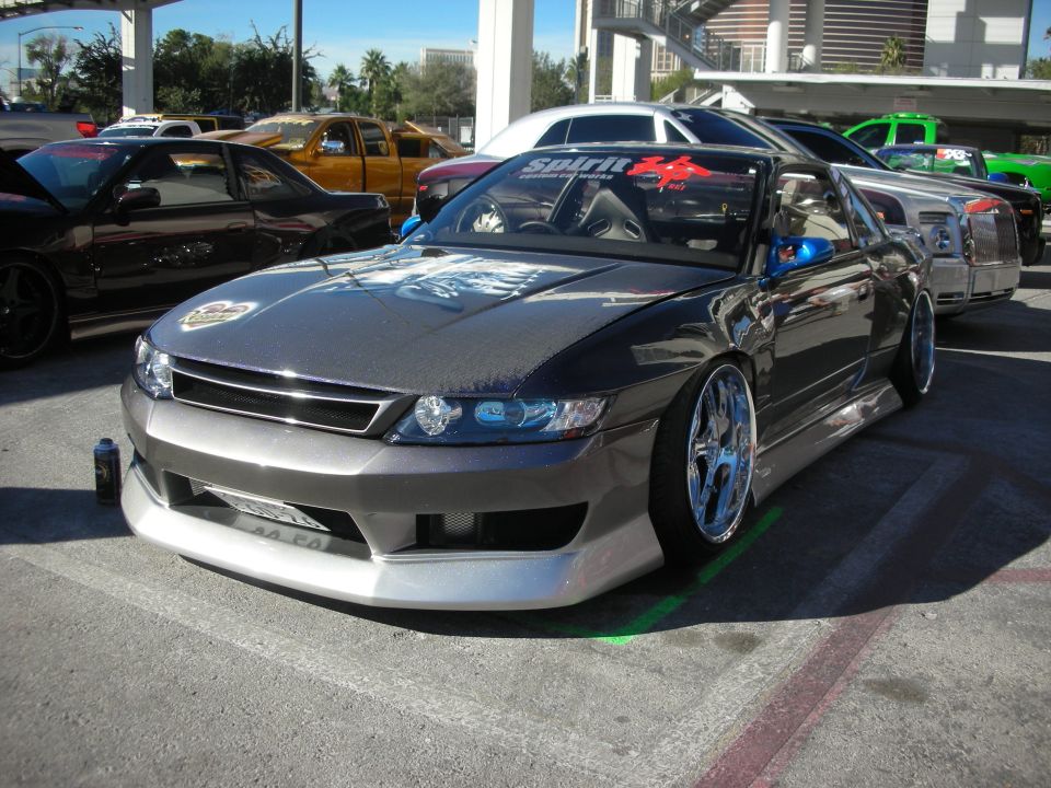 Gray custom Nissan coupe, slammed with body kit, at outdoor show
