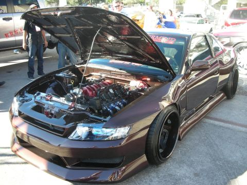 1998 Ford Crown Victoria - maroon custom coupe with its hood up revealing a turbocharged engine, fitted with a body kit and black wheels.