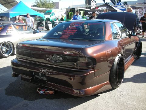 1998 Ford Crown Victoria - Rear three-quarter of a brown metallic custom coupe with a wide-body kit and dished black wheels at an outdoor show.