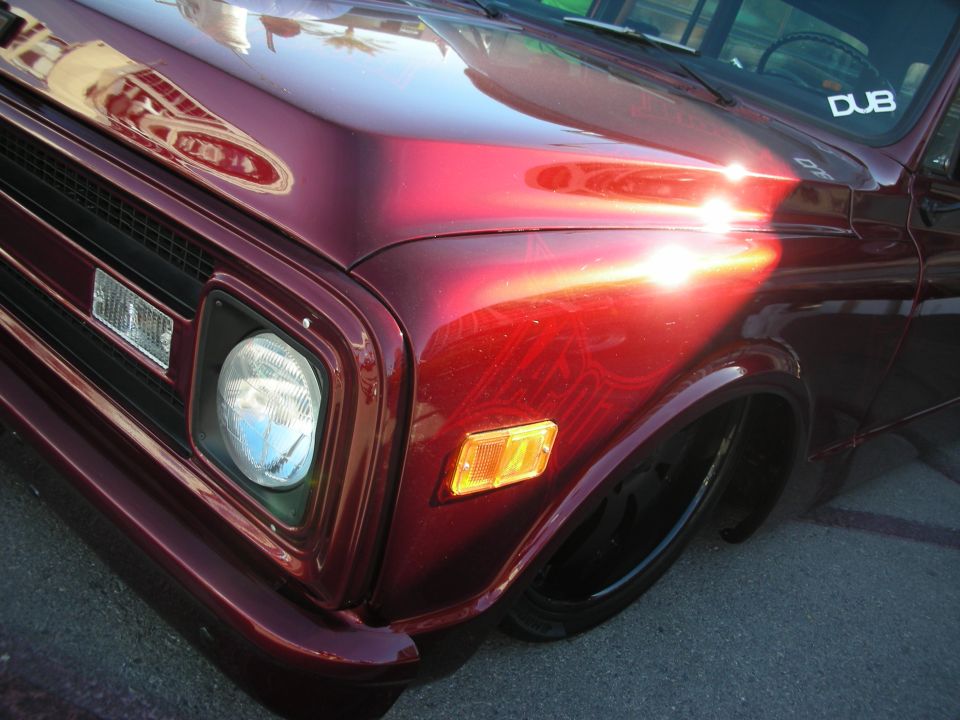 Close-up of the front fender and headlight of a dark red lowered classic truck