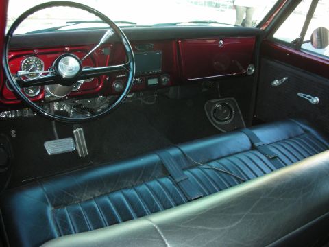 1998 Ford Crown Victoria - Interior of a classic vehicle showing a red dashboard, two-spoke steering wheel and black vinyl bench seat.
