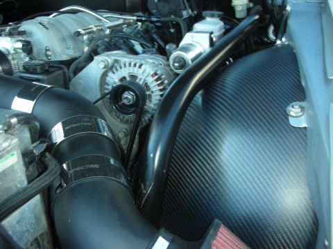 1998 Ford Crown Victoria - Close-up of an engine bay showing the alternator, polished tubing and a black carbon-fiber intake duct.