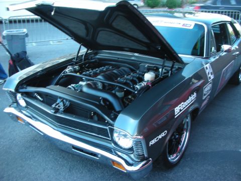 1998 Ford Crown Victoria - dark gray classic muscle car with hood up exposing the engine, wearing race and sponsor decals.
