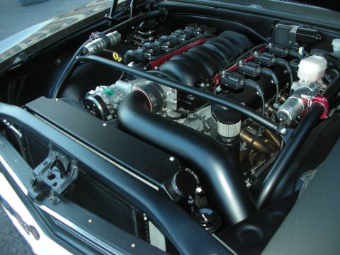 1998 Ford Crown Victoria - blacked-out LS V8 engine bay with twin black intake tubes, brake reservoirs and chrome detailing.