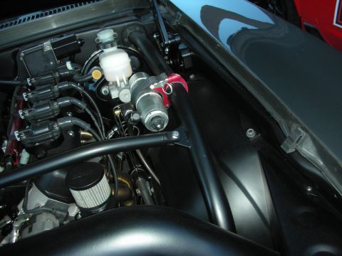 1998 Ford Crown Victoria - Engine bay detail showing the brake master cylinder, a red battery cutoff switch and black tube bracing.