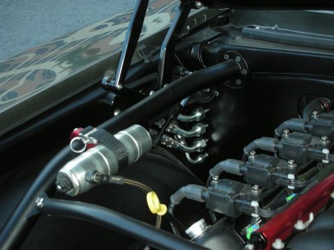 1998 Ford Crown Victoria - Detail of a custom engine bay with black tube bracing, a remote oil tank and stainless exhaust headers.