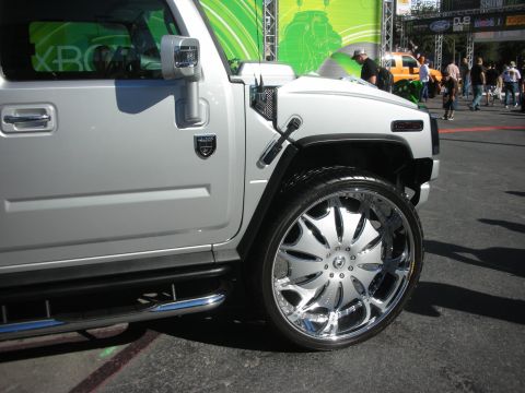 1998 Ford Crown Victoria - Front fender and door of a white Hummer fitted with an oversized chrome multi-spoke wheel at an outdoor event.