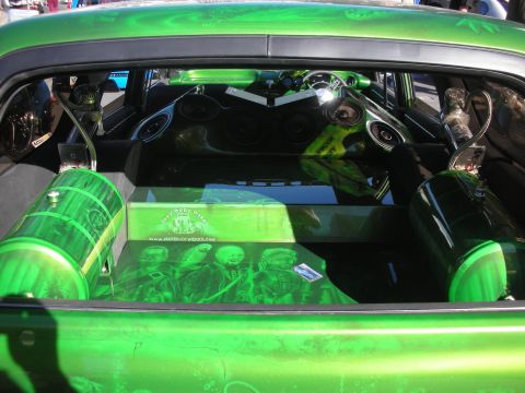 1998 Ford Crown Victoria - custom car's cargo area shows a green show audio install with subwoofers, amps and a printed plexiglass cover.