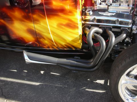 1998 Ford Crown Victoria - Close-up of a hot rod's wrapped exhaust headers running alongside its fire-flame painted body.