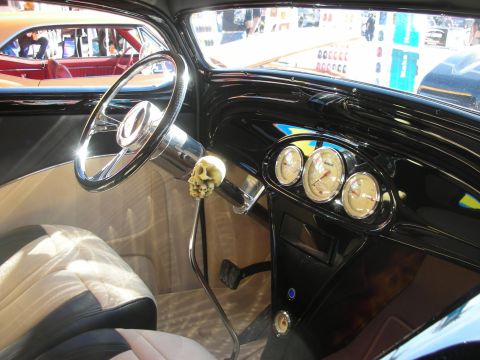 1998 Ford Crown Victoria - Hot rod cockpit showing a chrome steering wheel, round gauges, tan upholstery and a skull shift knob.