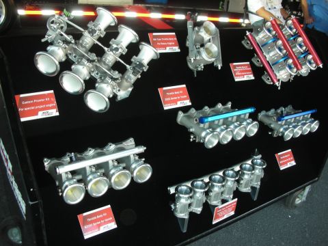 1998 Ford Crown Victoria - wall display of polished throttle-body and intake manifold kits with red descriptive labels.
