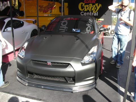 1998 Ford Crown Victoria - Front view of a matte gray Nissan GT-R with its GT-R grille badge and carbon lip at an outdoor show.