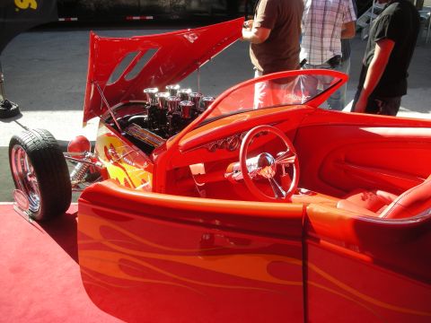 1998 Ford Crown Victoria - red flame-painted hot rod roadster with open hood showing a multi-carb engine and red leather interior.