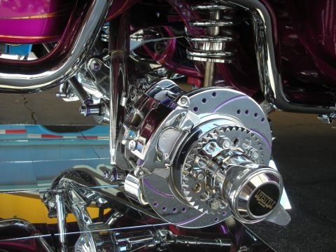 1998 Ford Crown Victoria - Close-up of a heavily chromed motorcycle rear drive featuring a drilled rotor, belt pulley and exposed shock.