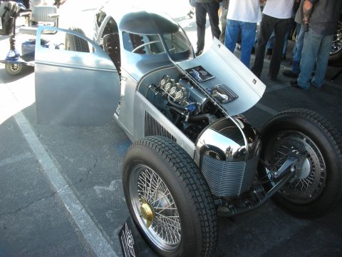 1998 Ford Crown Victoria - bare aluminum-bodied streamliner-style roadster with an exposed multi-carb inline engine and wire-spoke wheels.