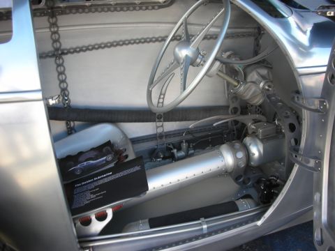 1998 Ford Crown Victoria - Cockpit of a bare-aluminum streamliner with a thin steering wheel, exposed chain drive and a 'Golden Submarine' info card.