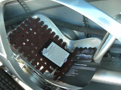 1998 Ford Crown Victoria - Interior detail of a silver streamliner showing a woven leather seat and a printed information card about the Golden Submarine.