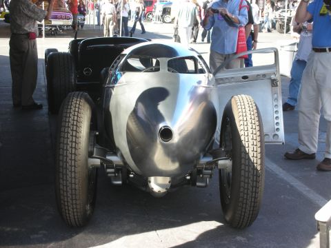 1998 Ford Crown Victoria - Rear of a polished aluminum bullet-bodied streamliner racer with tall narrow tires, viewed in an outdoor crowd.