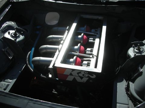 1998 Ford Crown Victoria - engine bay showing inline velocity stacks topped with red cone air filters and a K&N branded valve cover panel.