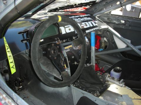 1998 Ford Crown Victoria - Stripped race-car cockpit featuring a suede flat-bottom steering wheel, roll cage and Snap-on/Mazdaspeed branding.