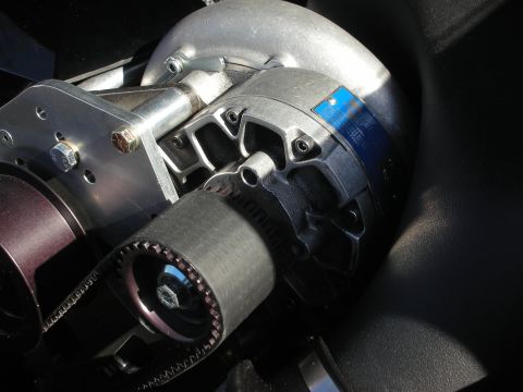 1998 Ford Crown Victoria - Detailed close-up of a belt-driven centrifugal supercharger and its cogged pulley mounted on an engine.