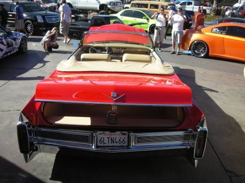 1998 Ford Crown Victoria - Rear view of a red convertible Cadillac with tan interior and a California license plate at an outdoor car show.