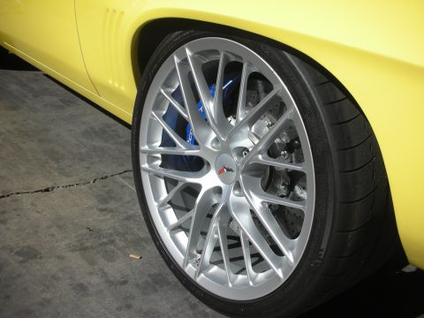 1998 Ford Crown Victoria - Close-up of a silver multi-spoke wheel and low-profile tire with a blue performance brake caliper on a yellow car.