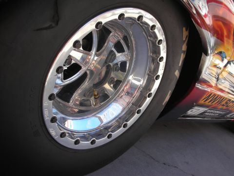 1998 Ford Crown Victoria - Close-up of a polished beadlock racing wheel mounted with a drag slick tire on a flame-painted vehicle.