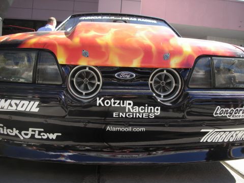 1998 Ford Crown Victoria - Front view of a black Ford race car with orange flame hood paint and sponsor decals including Kotzur Racing Engines.