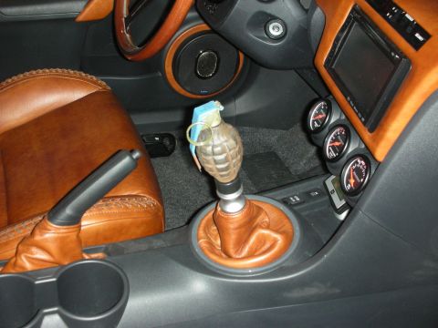1998 Ford Crown Victoria - Interior console of a car with tan leather seats, gauges and a hand-grenade-shaped manual shift knob.