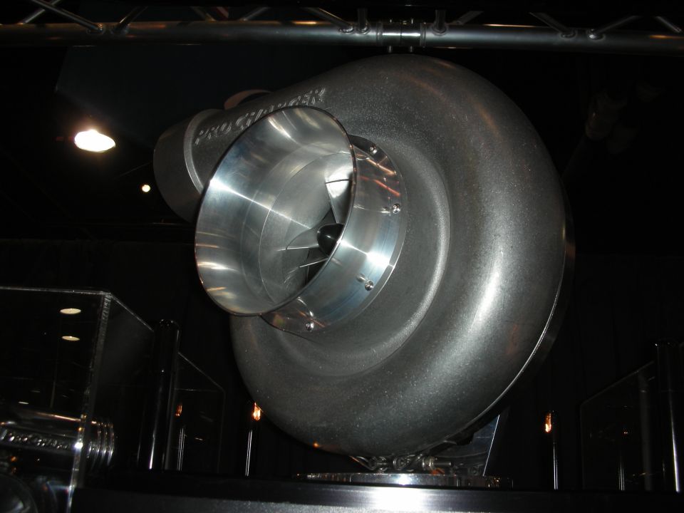 Large polished centrifugal supercharger displayed under lighting