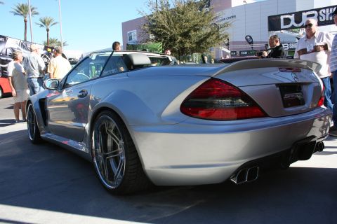 1998 Ford Crown Victoria - silver Mercedes-Benz SL convertible with custom polished wheels parked at an outdoor show beneath palm trees and DUB Show banners.