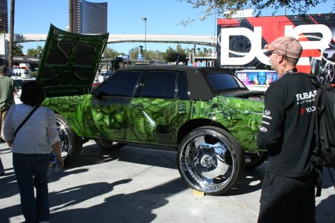 1998 Ford Crown Victoria - custom sedan airbrushed with green Hulk artwork sits on tall chrome wheels with a suicide door open at a DUB show.