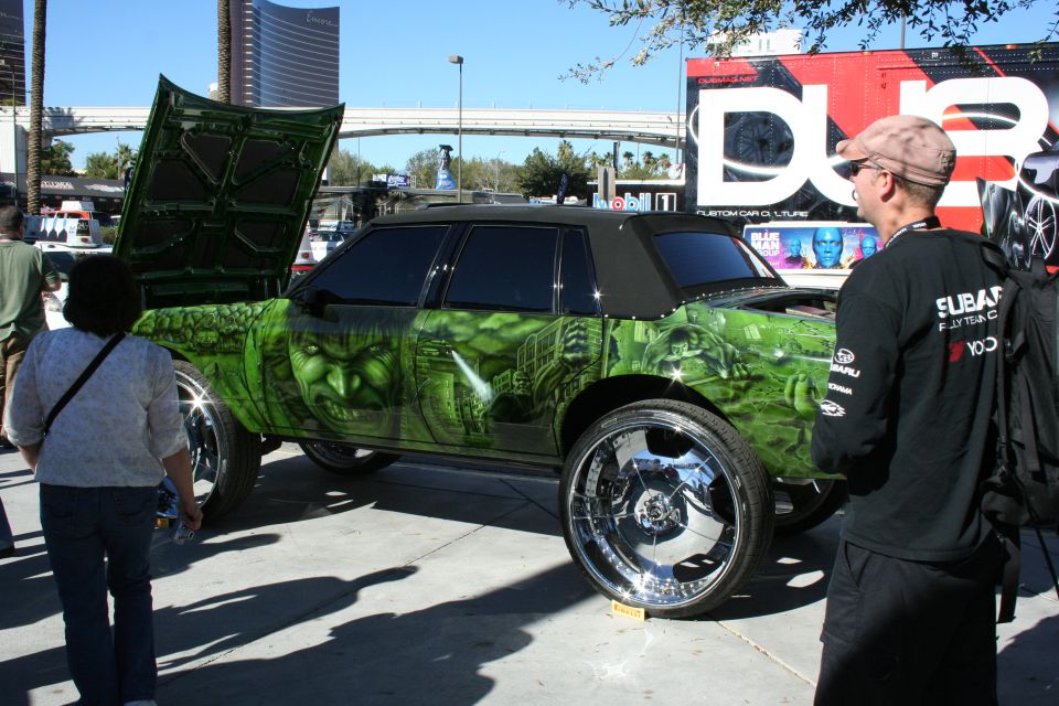 Green Hulk-themed custom car on large chrome wheels with open suicide door