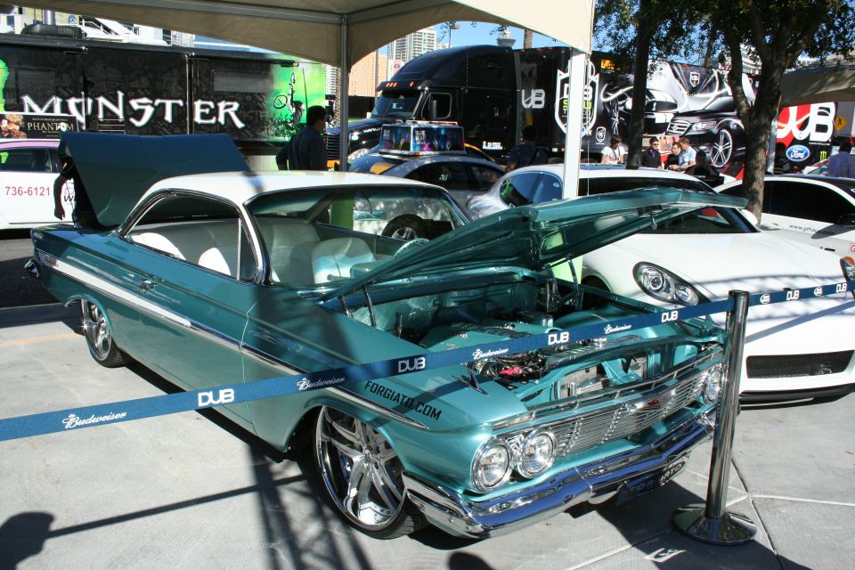 Teal custom Chevrolet Impala with open hood on chrome wheels at DUB show