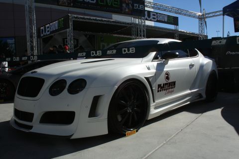 1998 Ford Crown Victoria - A white widebody coupe with custom body kit and black wheels is displayed at an outdoor event.