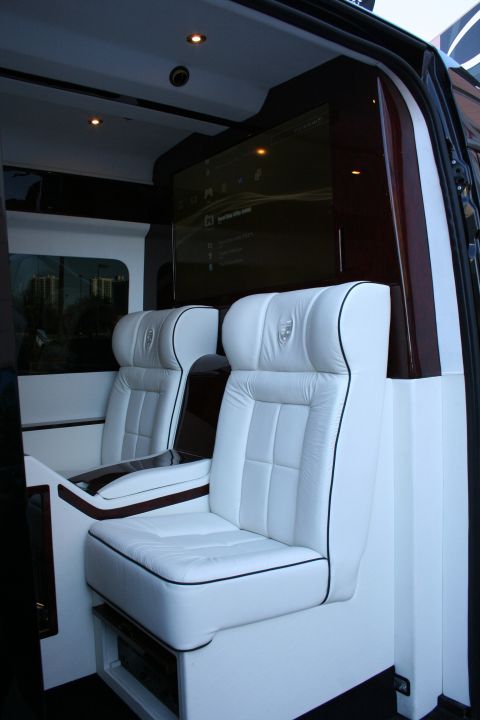 1998 Ford Crown Victoria - The interior of a van features plush white leather seats and a large entertainment screen.
