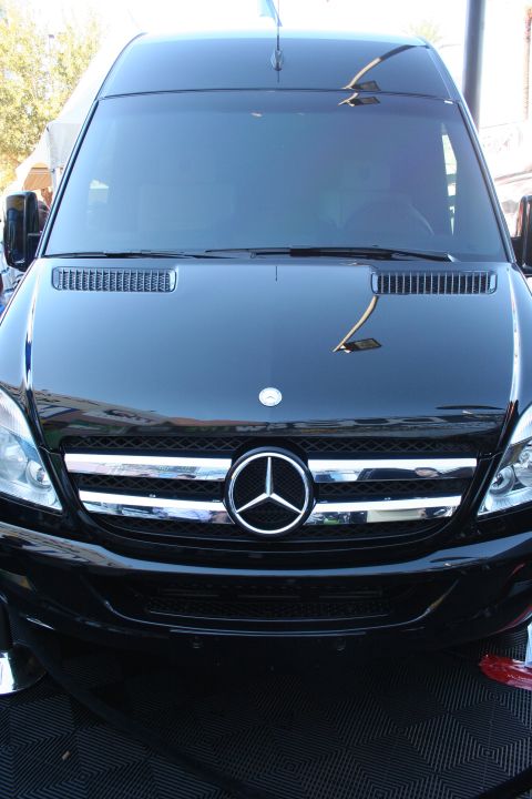 1998 Ford Crown Victoria - Front-end view of a glossy black Mercedes-Benz Sprinter van with chrome grille and three-pointed-star emblem.
