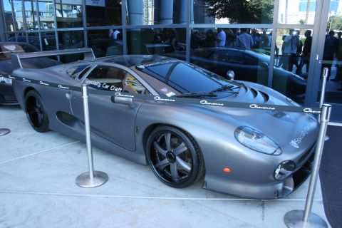 1998 Ford Crown Victoria - Matte gray Jaguar XJ220 supercar on display behind stanchions, wearing Giovanna and Specialty Car Craft decals.