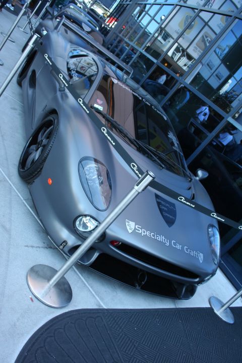 1998 Ford Crown Victoria - High angle view of a matte gray supercar with Giovanna and Specialty Car Craft decals roped off at a show.