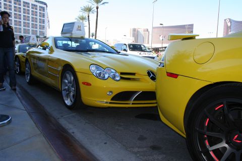 1998 Ford Crown Victoria - Front three-quarter view of a yellow Mercedes-Benz SLR McLaren parked next to another yellow car on a street.